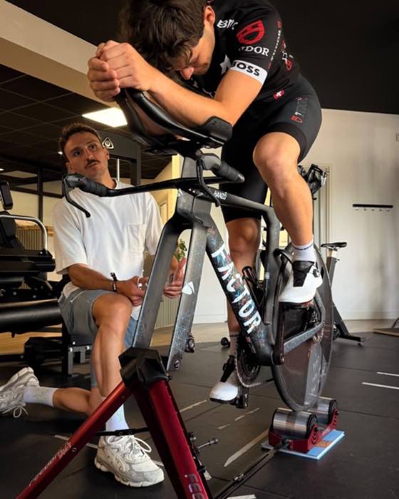 Séance de bike fitting : un cycliste pédale sur home-trainer pendant que le kinésithérapeute analyse sa position.